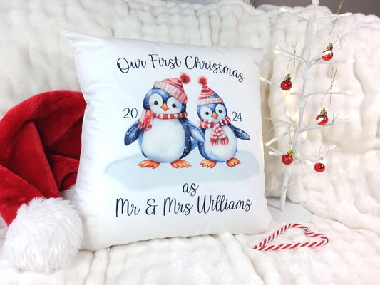 Decorative pillow with penguins and text 'Our First Christmas as Mr & Mrs Williams' on a festive background.