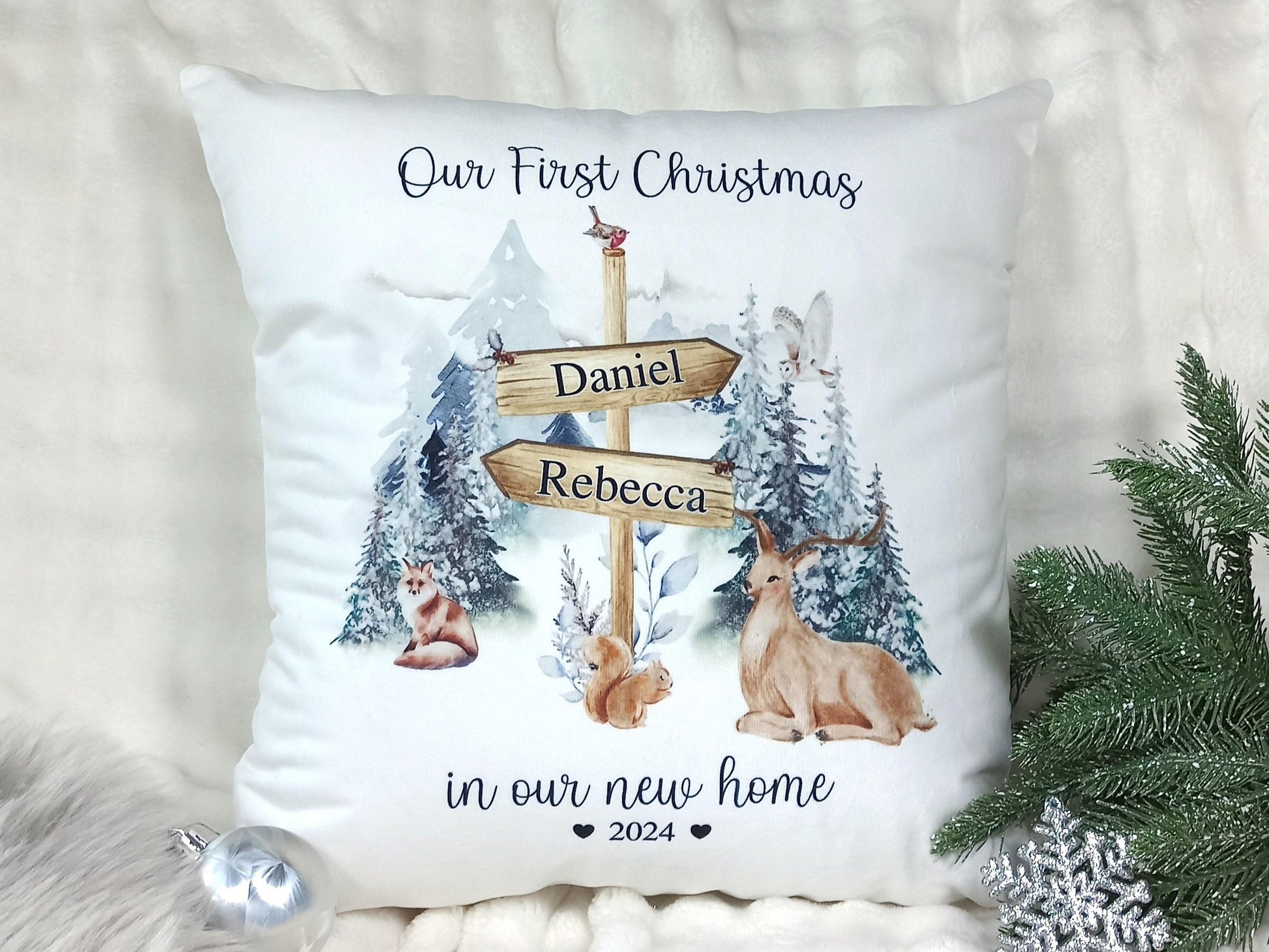 Decorative pillow with Christmas design featuring a signpost, trees, and animals on a white background.